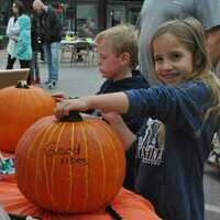 Thalia Sanders, 8, of Marlow, daughter of Kristi Sanders, shows off her painted pumpkin “Good Vibes” at the Choice Hospice booth. Ethan Garrett, 6, begins work on his pumpkin next to her.
