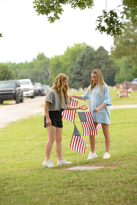 Macy Heaton, right, and Paizli Heaton, volunteered a few hours Saturday, May 27, 2023, to help Earl and Pat Lavey replace and add American flags to the grave sites of American service members. Photo by Toni Hopper/The Marlow Review