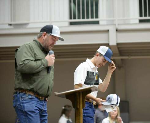 Korben Baker adjusts his FFA ballcap in a moment of humbleness as he listens to his father, Kenny, talk about how proud he is of him. The elder Baker served as auctioneer for this year’s annual Marlow FFA Labor Auction fundraiser, held Dec. 1, 2022, at the First Baptist Church Life Center. Photo by Toni Hopper/The Marlow Review
